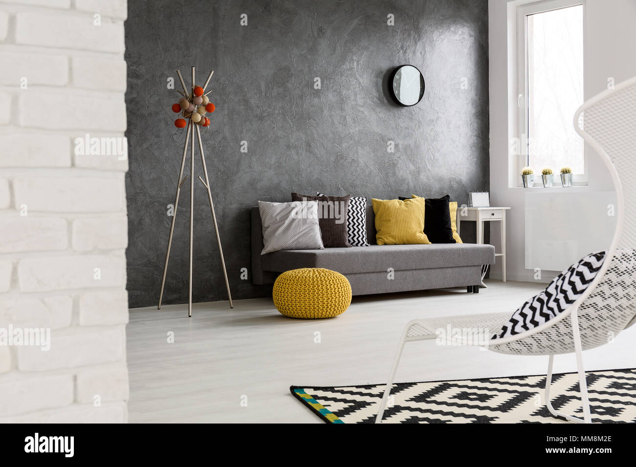 Modern, grey interior with sofa, chair, yellow details and stylish decorations Stock Photo