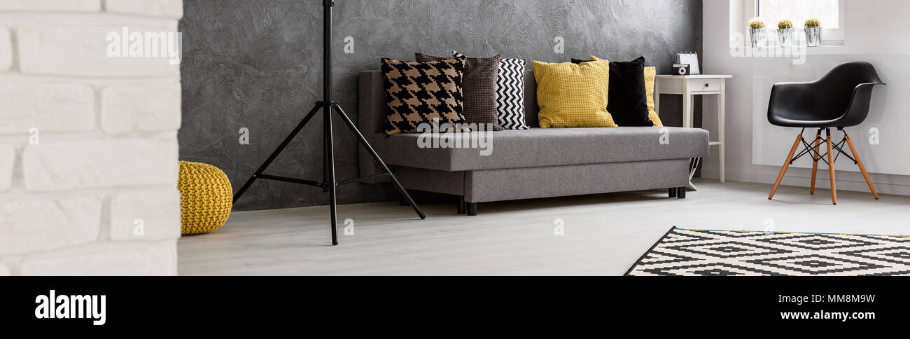 Panorama of a modern interior with brick and stucco walls, with grey sofa in the middle Stock Photo