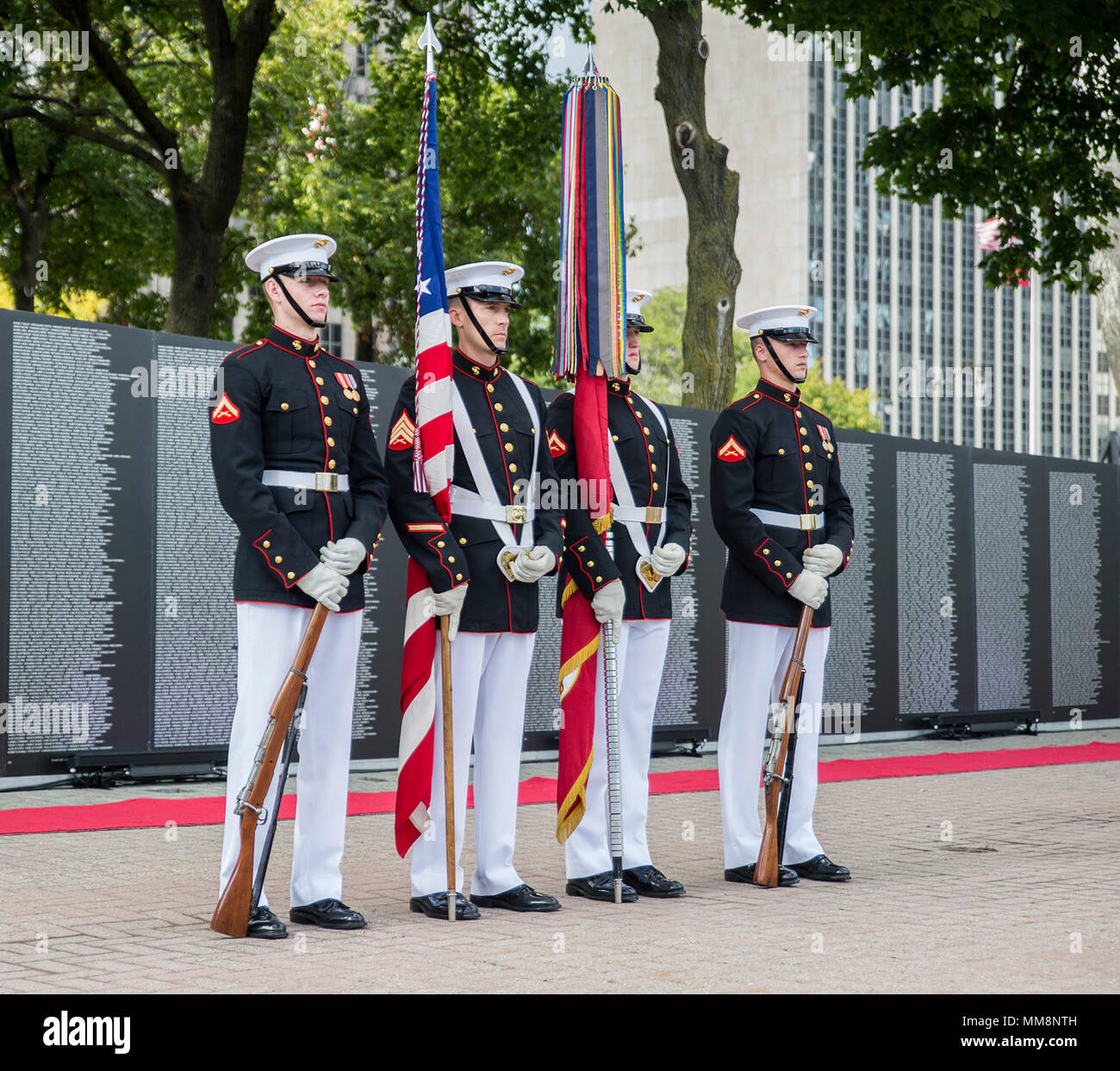The U.S. Marine Corps Color Guard post at a ceremonial position alongside the Traveling Vietnam Memorial Wall after the conclusion of a Vietnam War pinning ceremony as a part of Marine Week, Detroit, MI., Sept. 8, 2017. The memorial was set up alongside the Detroit Riverwalk where ten Vietnam veterans received commemorative pins to honor their service and sacrifice to our country. (Official U.S. Marine Corps photo by Cpl. Robert Knapp/Released) Stock Photo