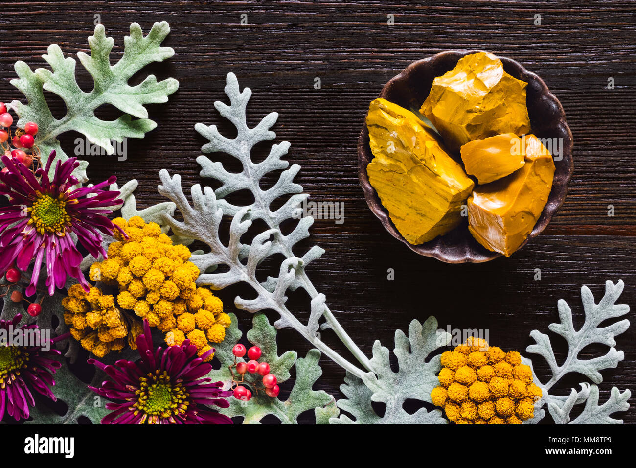 Yellow Jasper Stones with Dusty Miller, Clustered Everlasting and Chrysanthemums on Dark Table with Space for Copy Stock Photo