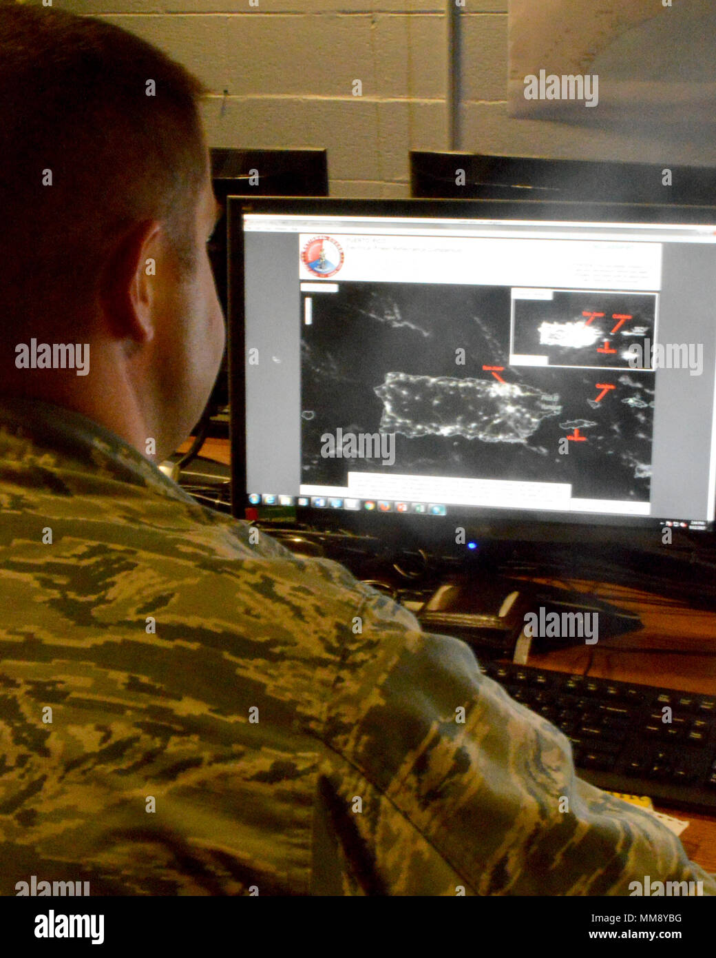 Capt. Charles, an intelligence officer for the 118th Intelligence, Surveillance, and Reconnaissance Group based at Joint Base Berry Field in Nashville, Tenn., assesses areas in Puerto Rico without power. The box in the top right of his screen is a before image provided by NASA, and the main image is the current power situation on September 15. Stock Photo