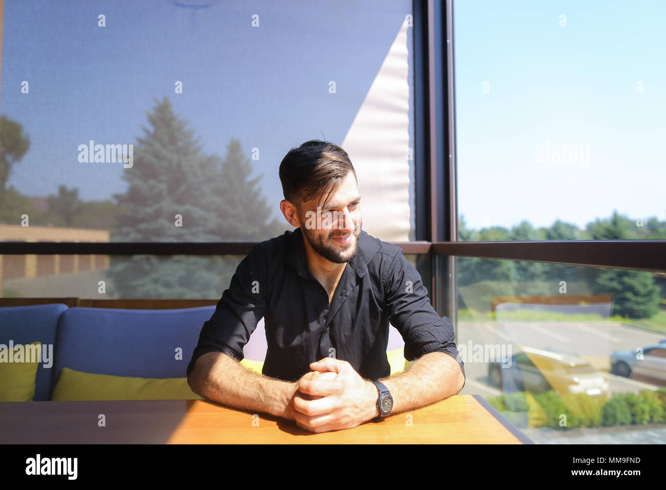 Young businessman sitting at office on sofa and wearing black shirt. Stock Photo