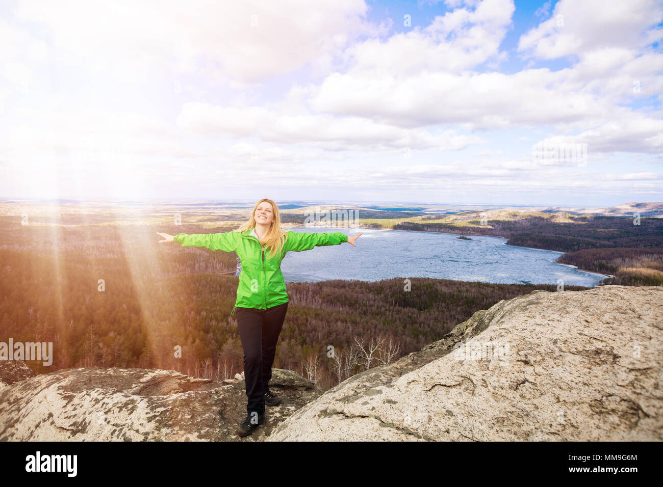 Young woman standing on cliff edge with raised hands Stock Photo - Alamy