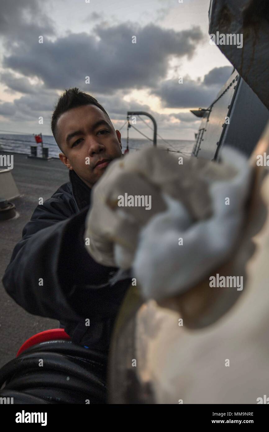 170919-N-FP878-025 ATLANTIC OCEAN (Sept. 19, 2017) Culinary Specialist 2nd Class Julian Fuenzalida, from Virginia Beach, Virginia, polishes the ships bell as the Arleigh Burke-class guided-missile destroyer USS Donald Cook (DDG 75) transits the Atlantic Ocean Sept.19, 2017.  Donald Cook, forward-deployed to Rota, Spain, is on its 6th patrol in the U.S. 6th Fleet area of operations in support of regional allies and partners, and U.S. national security interests in Europe. (U.S. Navy photo by Mass Communication Specialist 1st Class Theron J. Godbold /Released) Stock Photo
