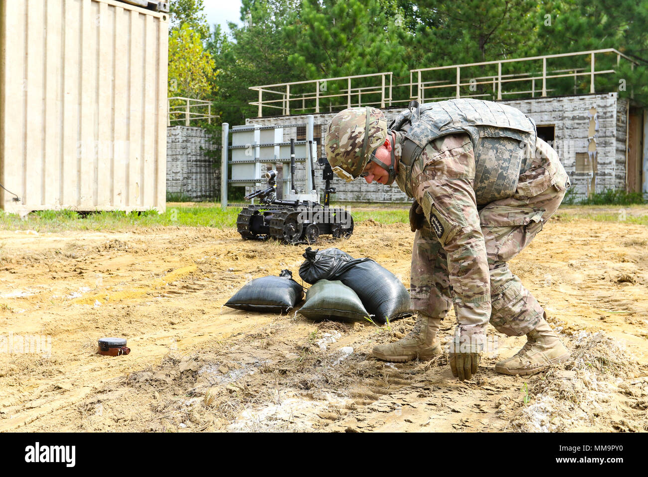 Sgt. 1st Class Joshua Tygret, assigned to 744th Ordnance Disposal Company,  52nd Explosive Ordnance Group, uses his hand to mark the perimeter of a  horseshoe-shaped protective wall that he will construct out