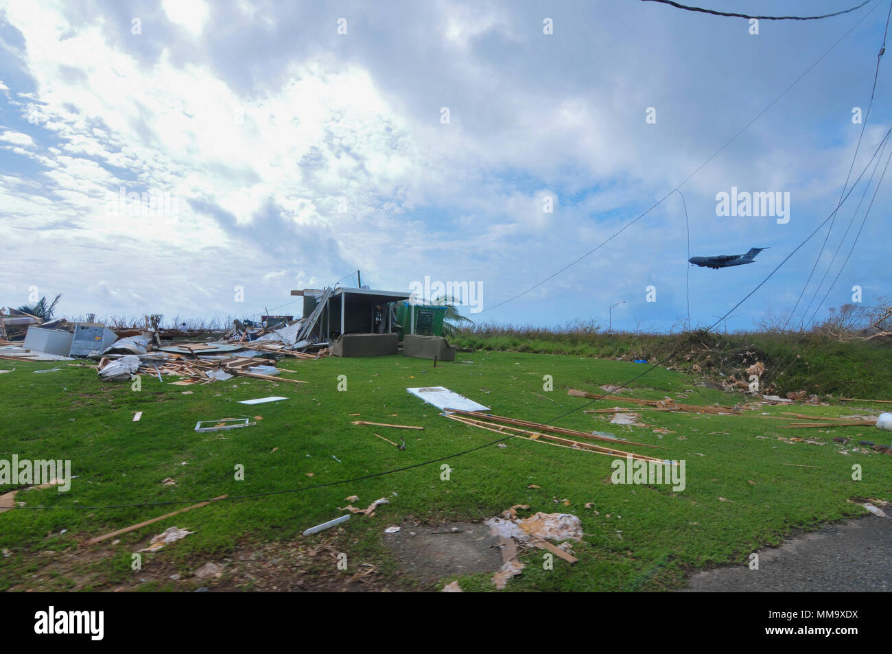 A C17 aircraft flies over the remnants of a house ravaged by Hurricane