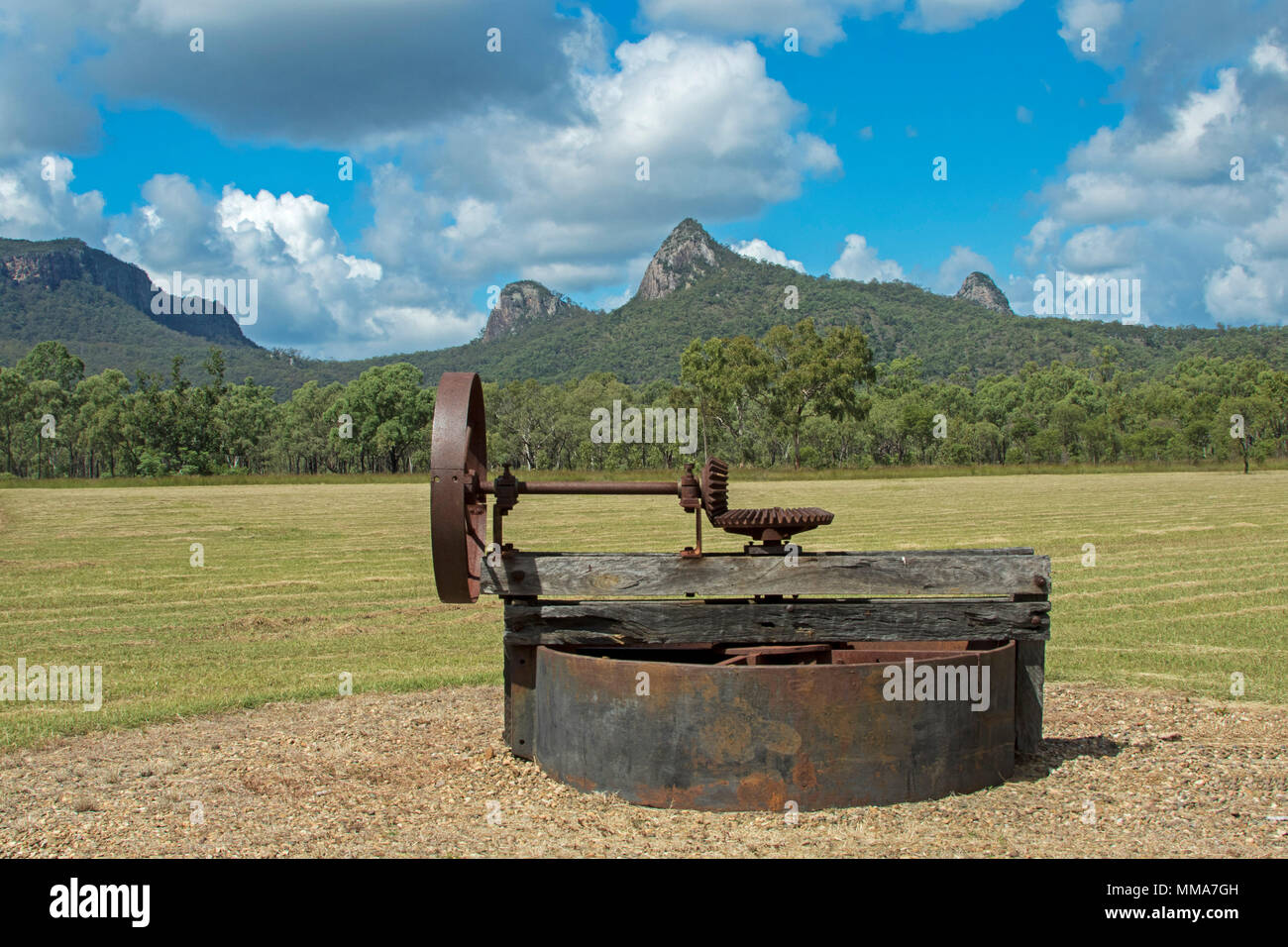 Site of historic mining town of Mount Britton with relics of past beside woodlands at foot of jagged peaks of Great Dividing Range under blue sky Stock Photo