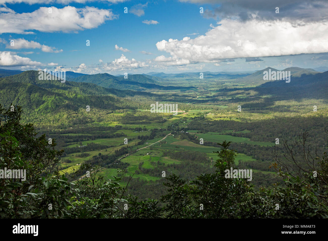 Vast landscape of verdant valley and farmlands hemmed by forested peaks of Great Dividing Range under blue sky in northern Queensland Australia Stock Photo