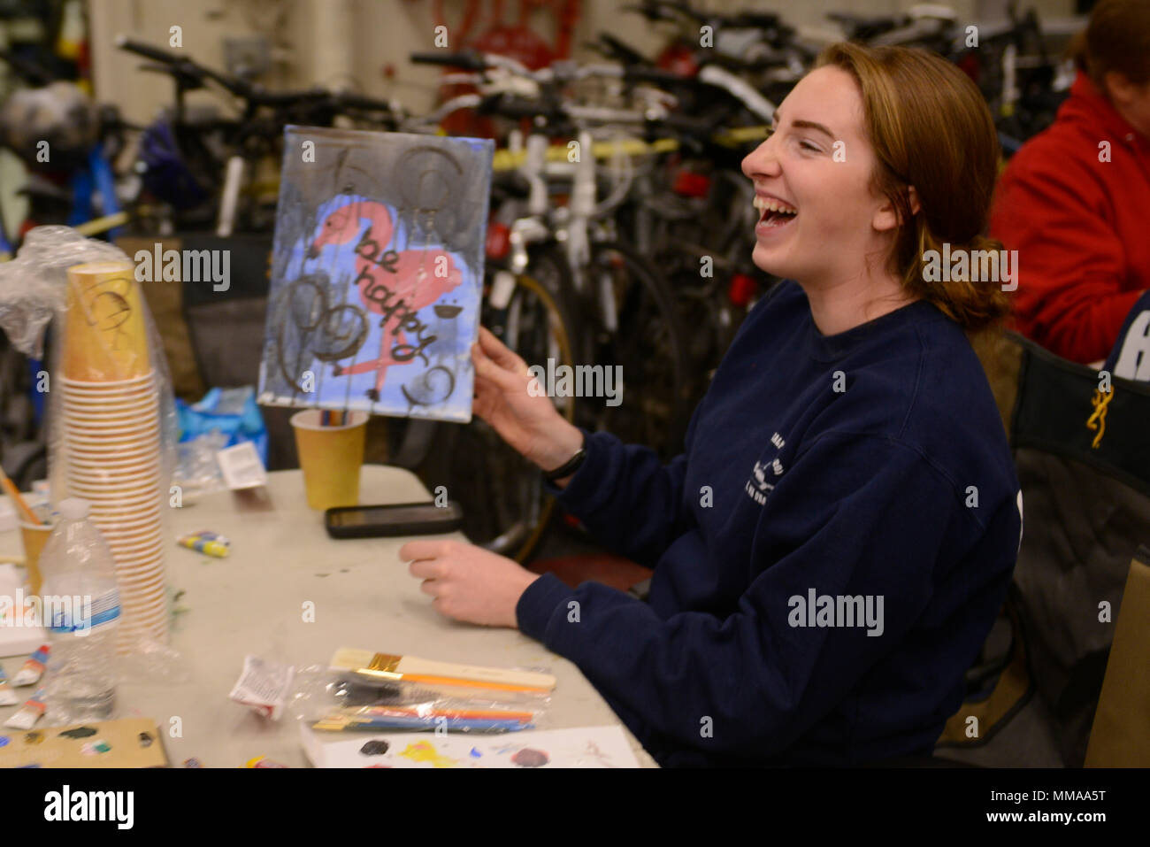 Coast Guard Ensign Jennifer Haley laughs at her painting, during a