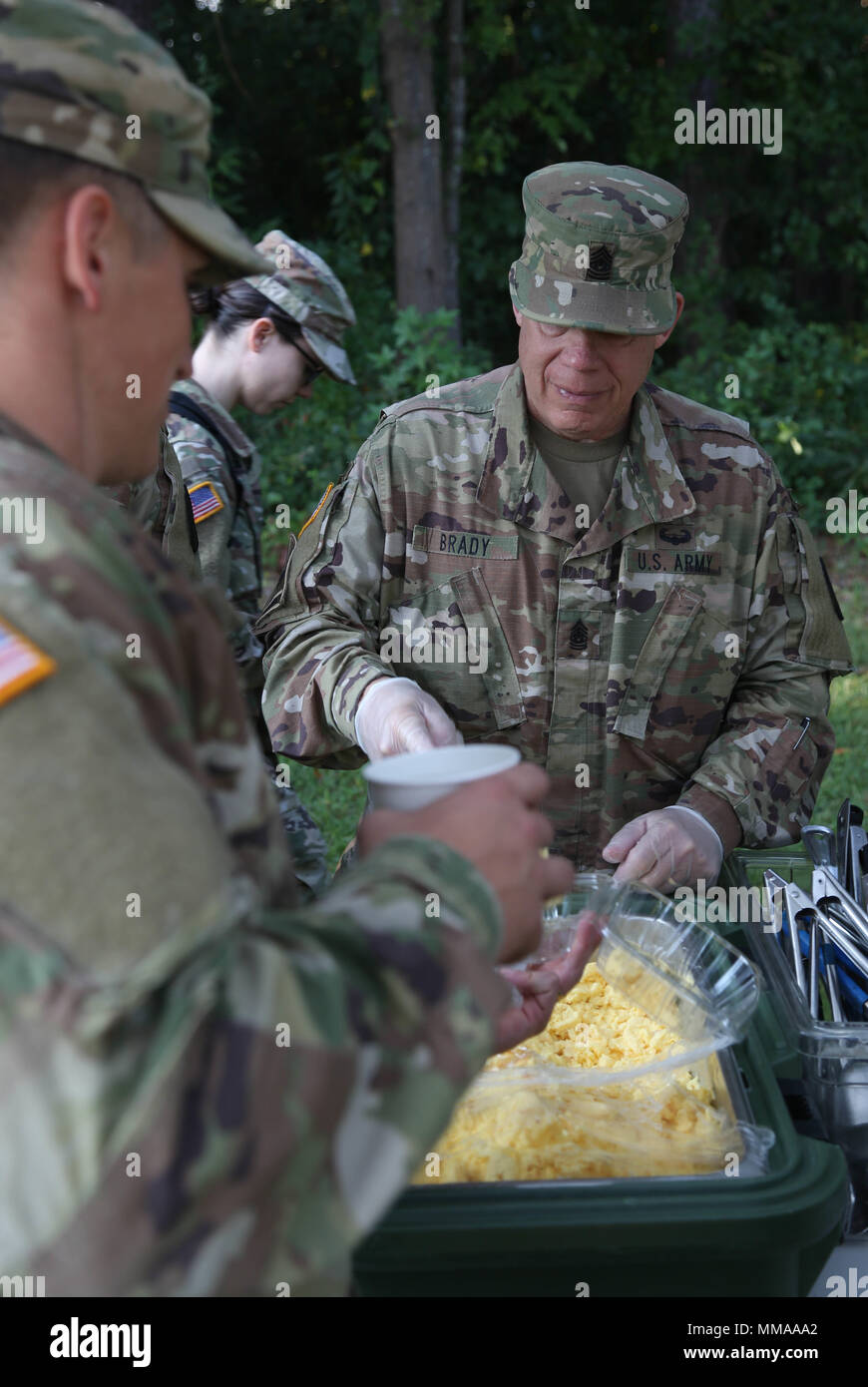 U.S. Army Command Sgt. Maj. Matthew Brady, assigned to Regional Health Command - Atlantic, serves hot breakfast to the competitors after the 2017 Best Medic Competition at Fort Bragg, N.C., Sept. 20, 2017. The competition tested the physical and mental toughness, as well as the technical competence, of each medic to identify the team moving forward to represent the region at the next level of the competition.  (U.S. Army photo by Pfc. Meleesa Gutierrez) Stock Photo