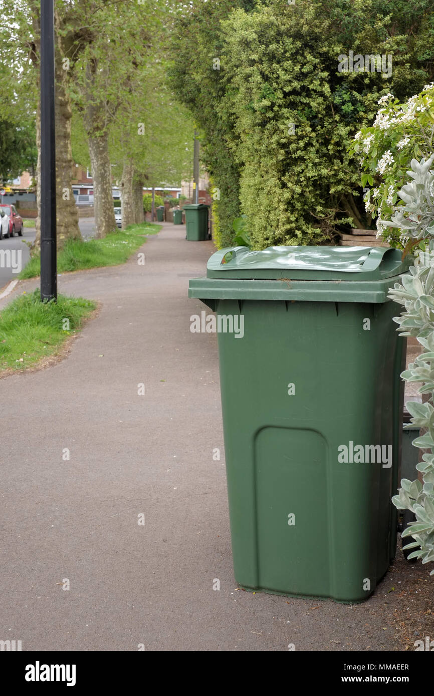 May 2018 - Green garden waste recycling bins on a leafy suburban street in Portishead, North Somerset. Near Bristol, England. Stock Photo