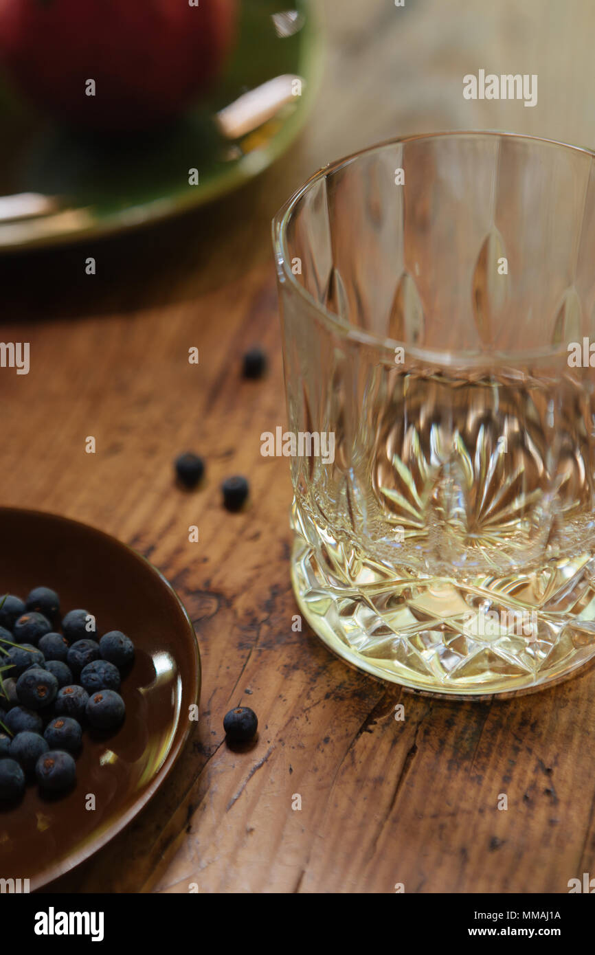 A glass of gin with juniper berries (Juniperus Communis) on a rustic