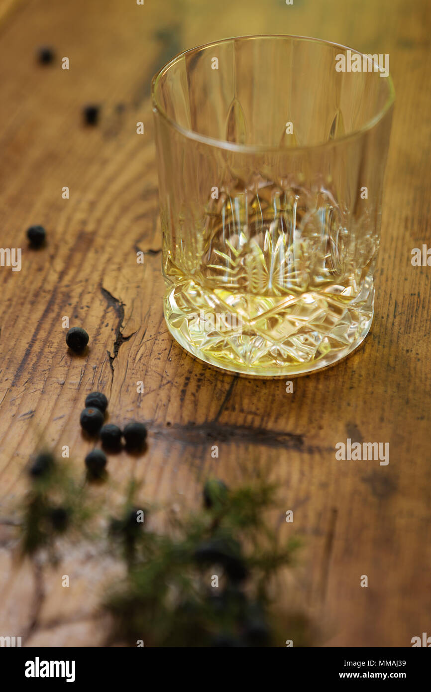 A glass of gin with juniper berries (Juniperus Communis) on a rustic table Stock Photo