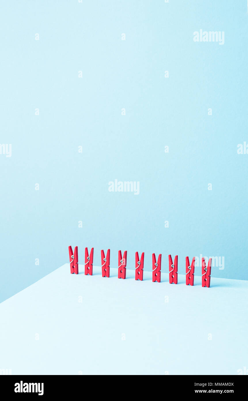 Red laundry clips organized in a row over blue background Stock Photo