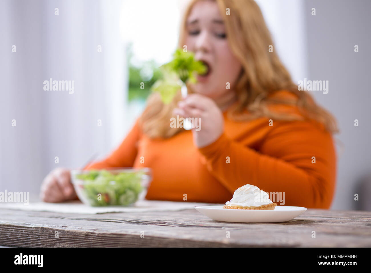 Determined plump woman looking at cookies Stock Photo