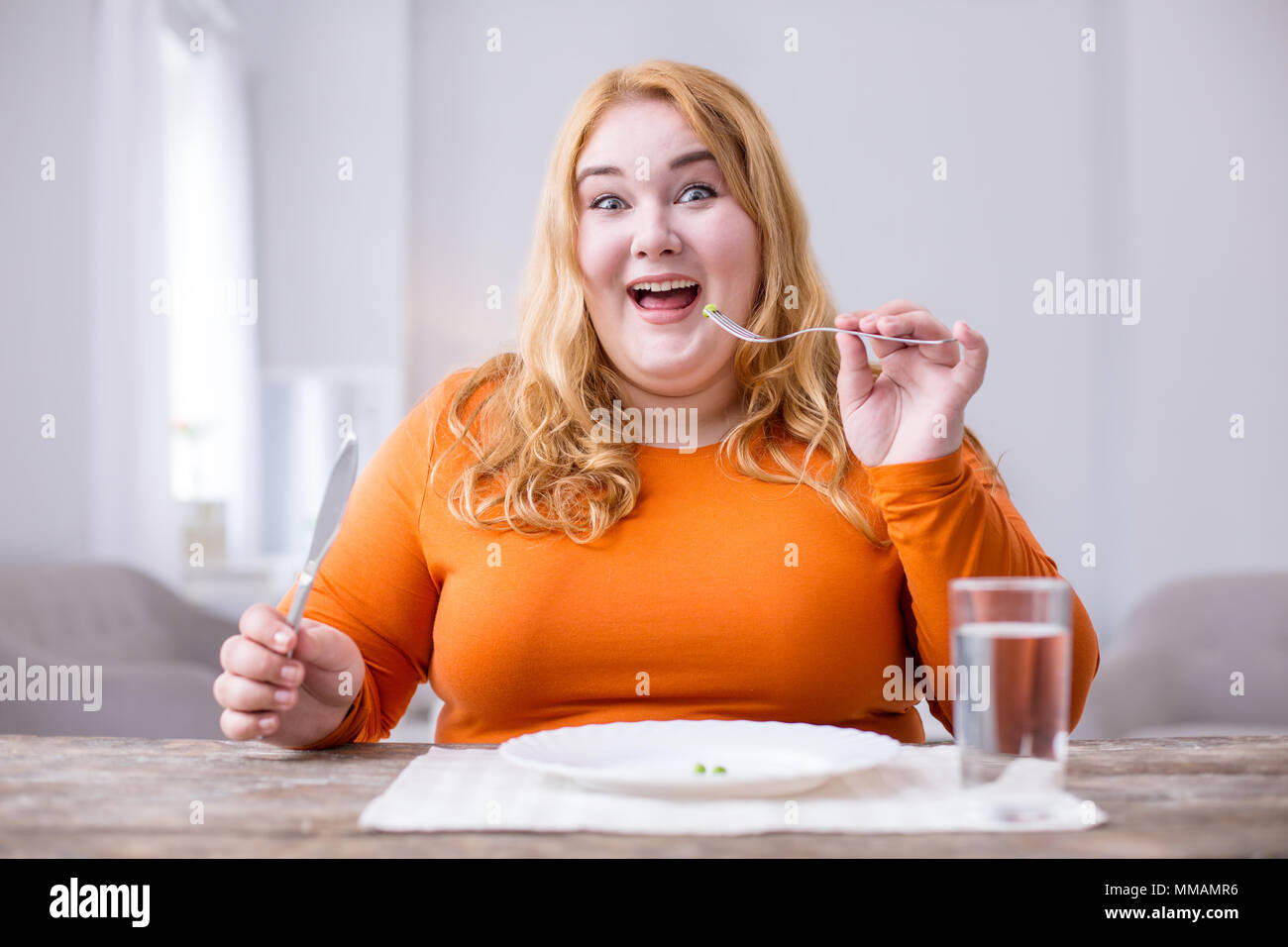 Alert fat woman having peas for breakfast Stock Photo