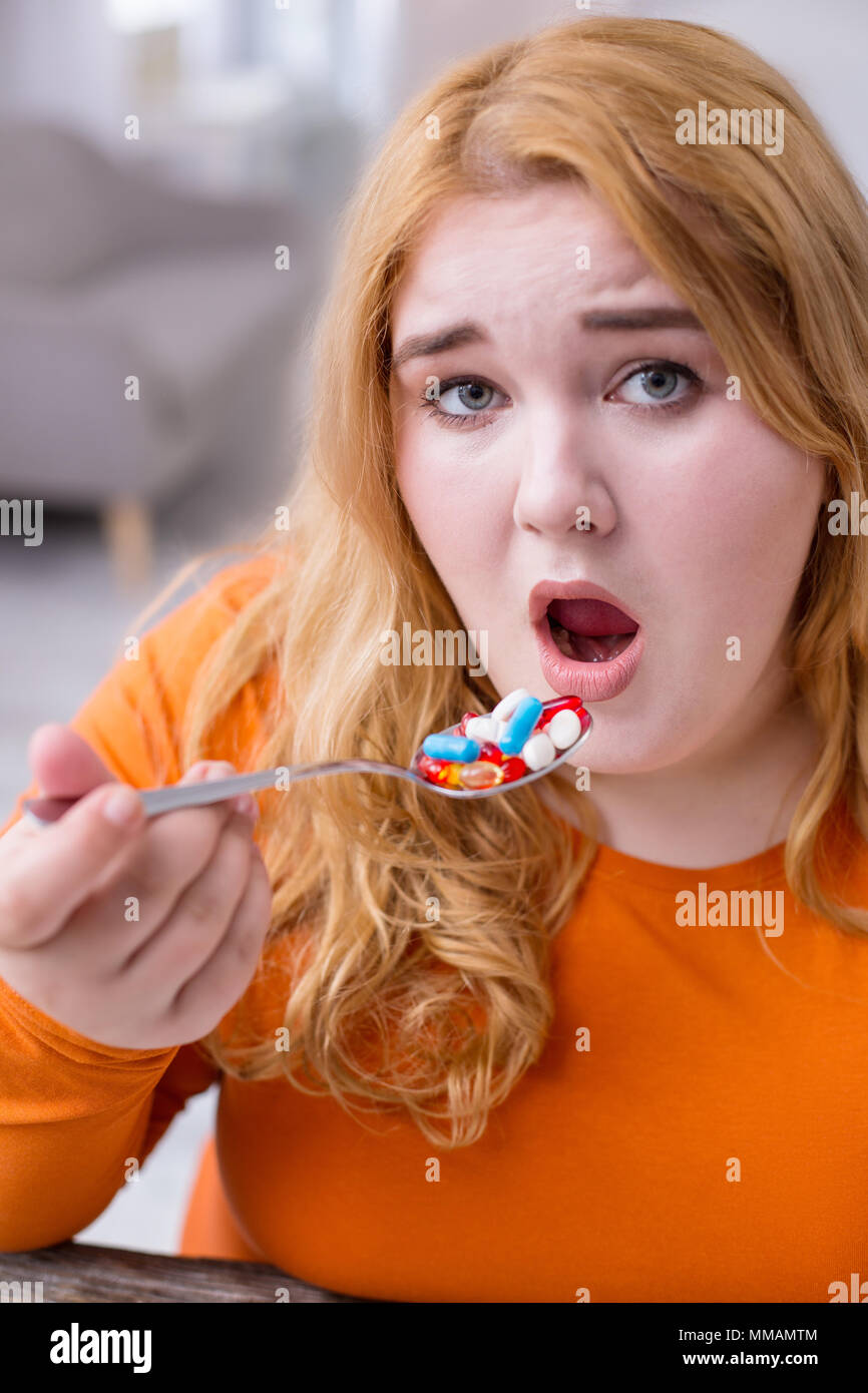 Dissatisfied stout woman taking medications Stock Photo - Alamy