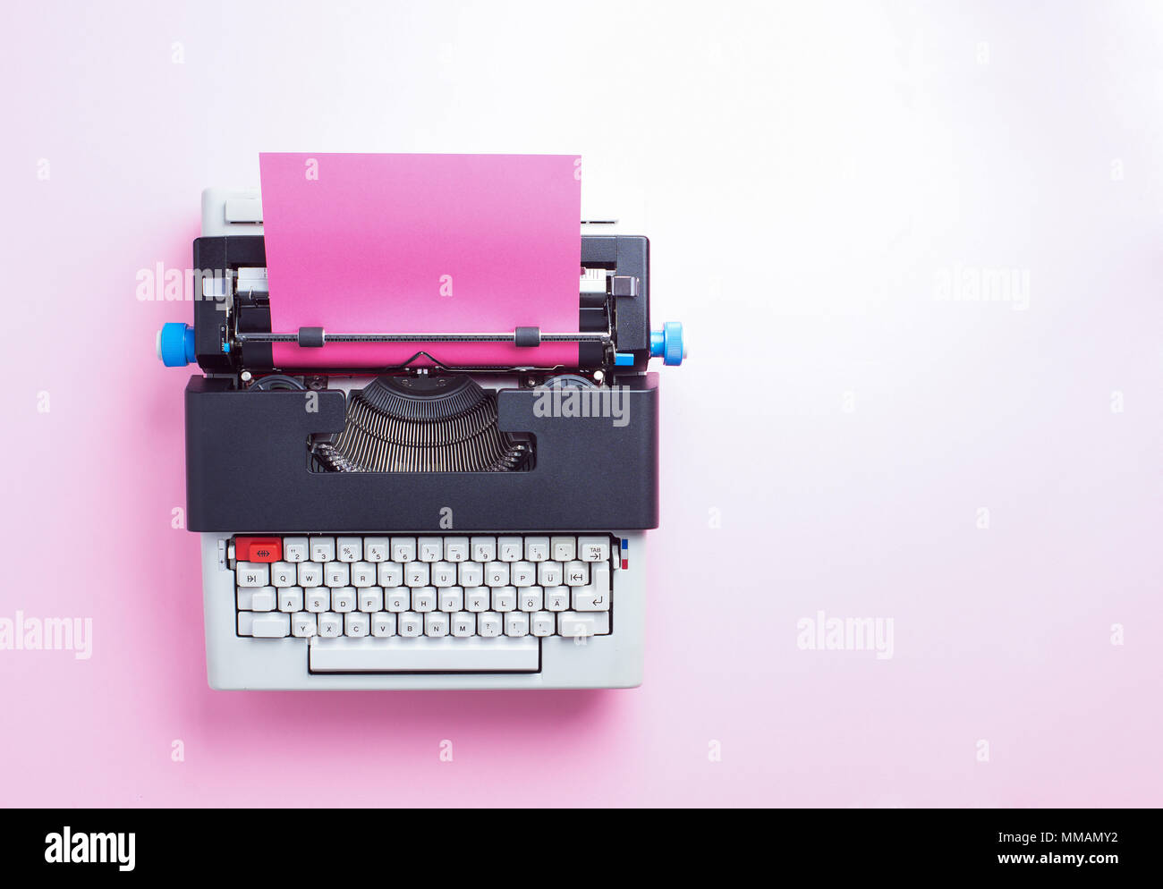 Typewriter with pink paper over blue background, top view Stock Photo