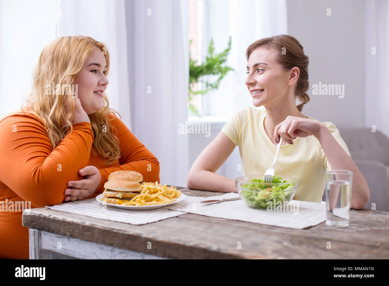Joyful fat woman having lunch with her friend Stock Photo