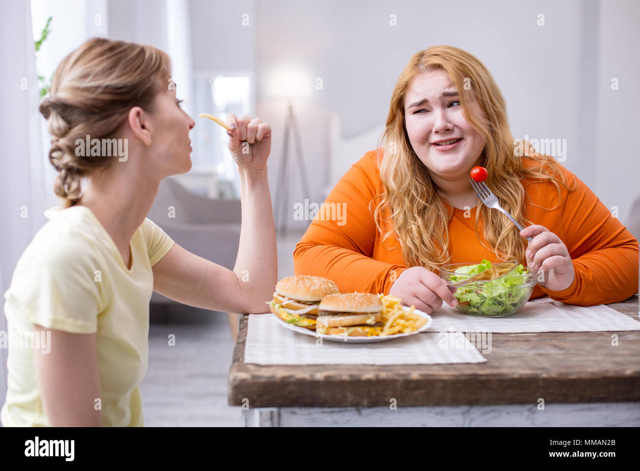 Miserable plump woman having lunch with her friend Stock Photo