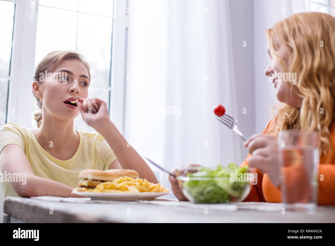 Serious slim woman having lunch with her friend Stock Photo