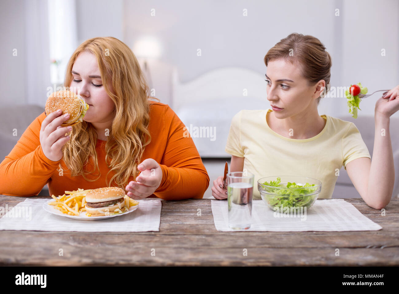 Cheerful plump woman having lunch with her friend Stock Photo