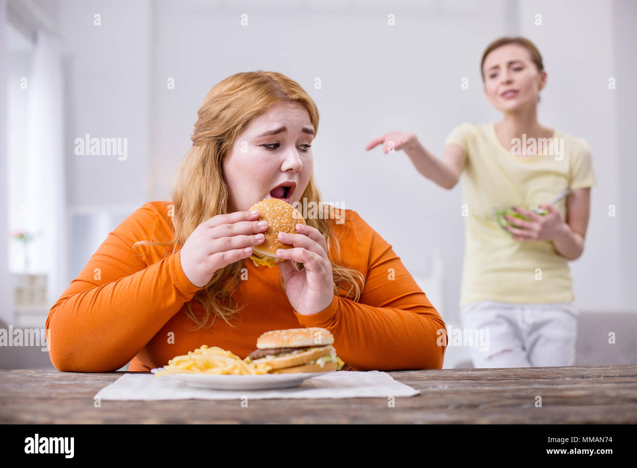 Miserable plump woman eating a sandwich Stock Photo
