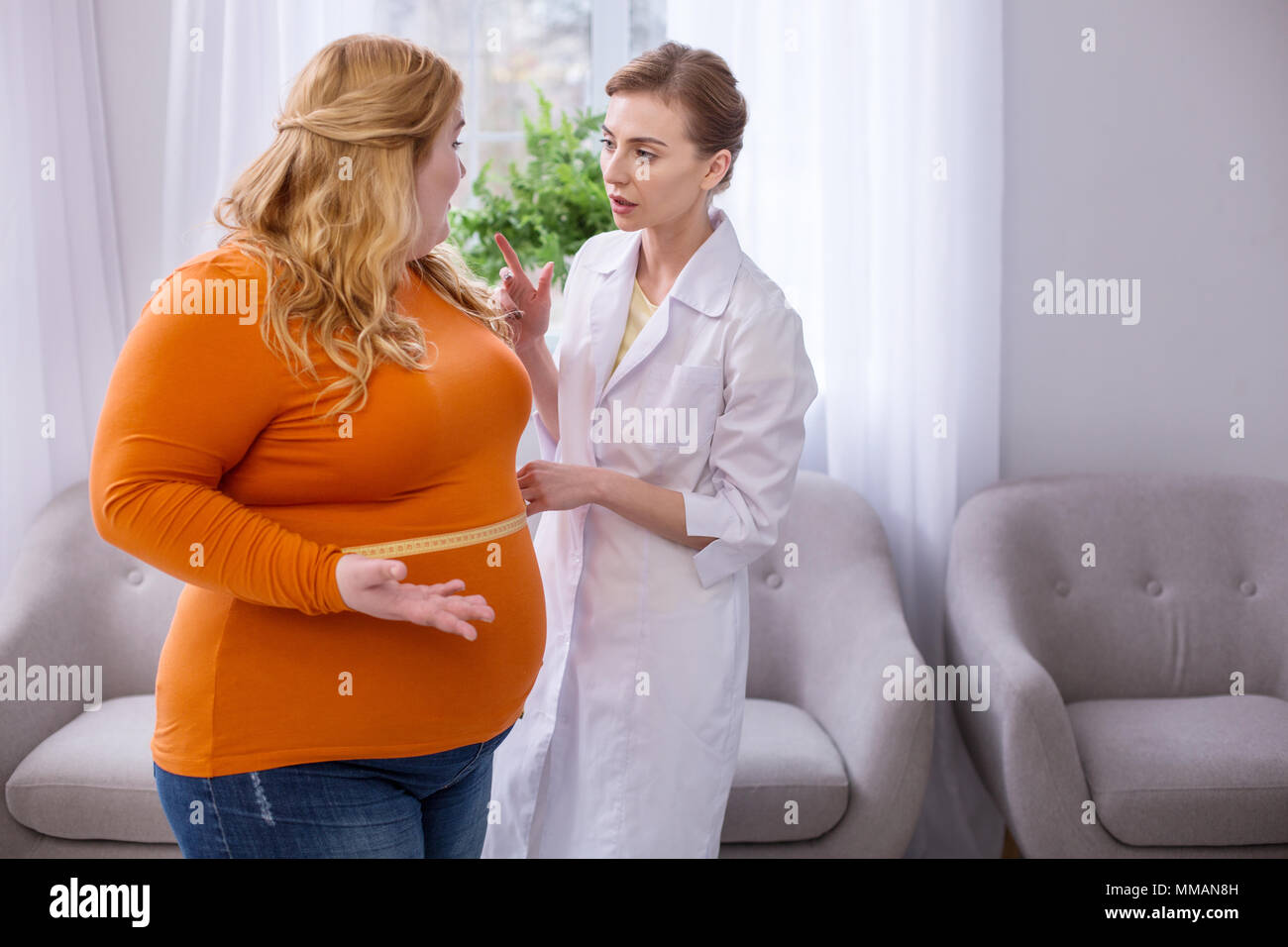 Serious doctor talking with a plump woman Stock Photo