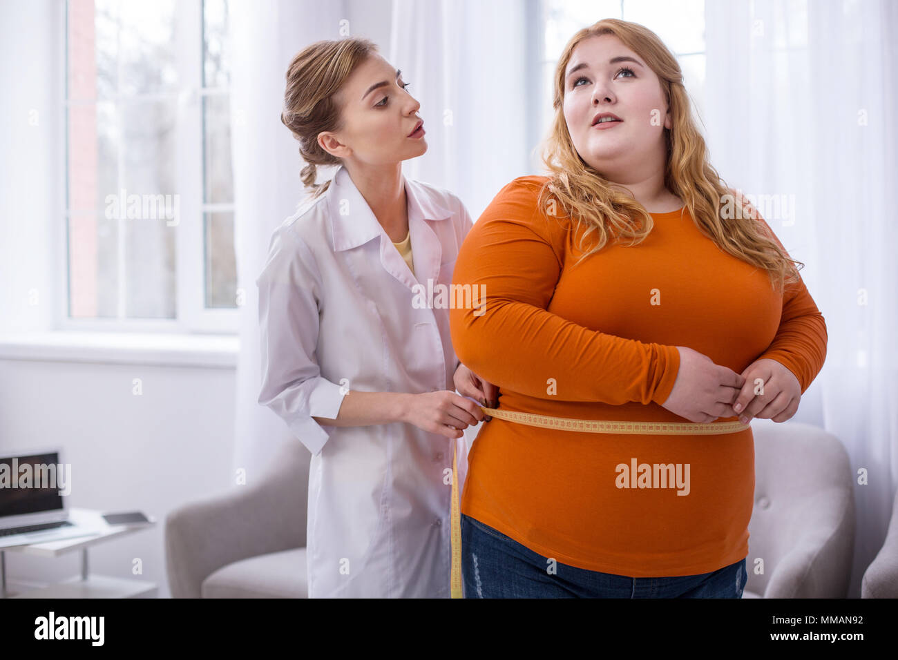 Concentrated doctor talking with a plump woman Stock Photo