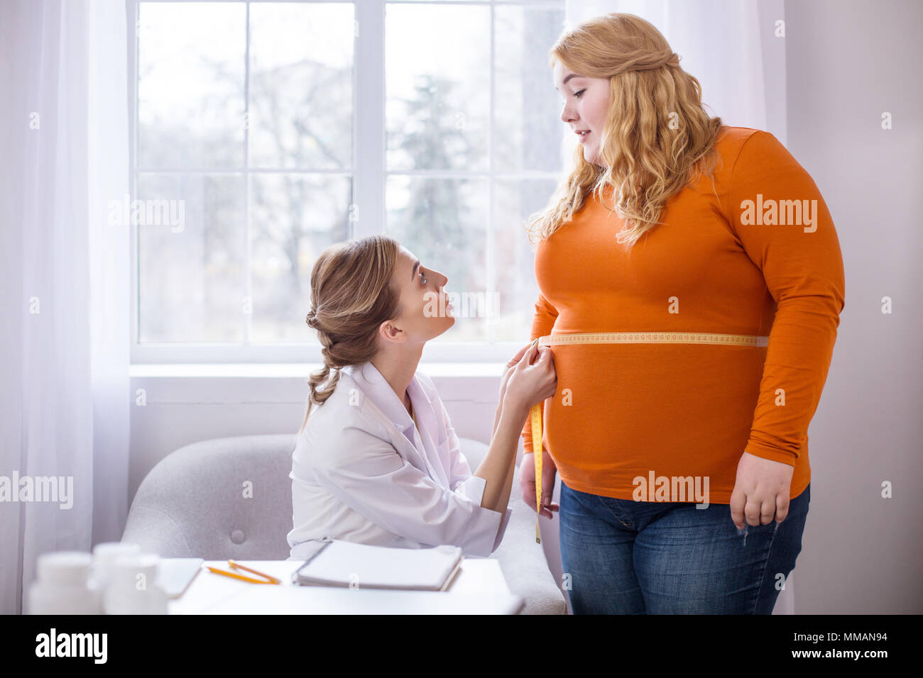 Dissatisfied doctor talking with a plump woman Stock Photo