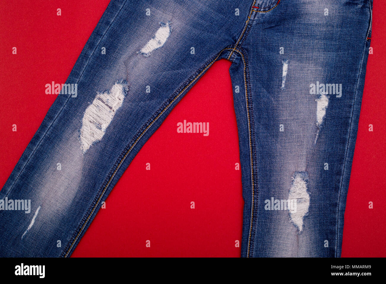 Ripped jeans light blue on a red background Stock Photo Alamy