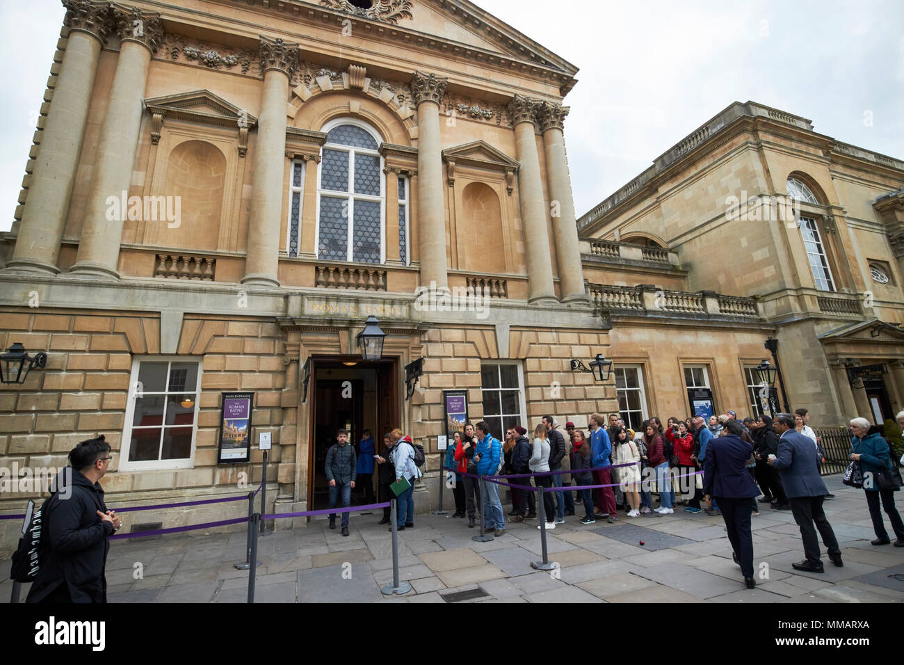 queues of tourists waiting in line to enter the roman baths complex abbey churchyard Bath England UK Stock Photo