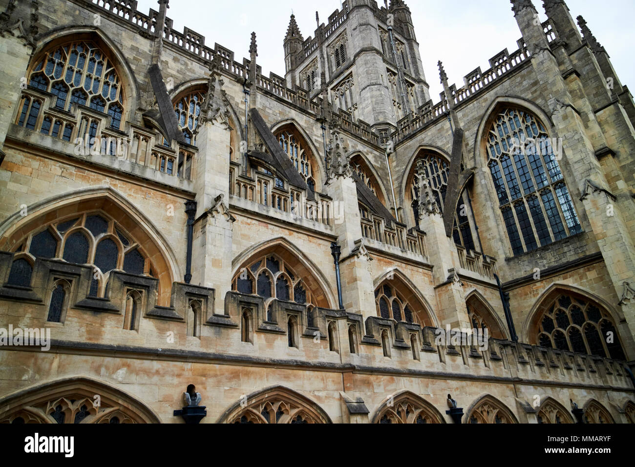 side view looking up at flying buttresses, battlements, pinnacles and parapets of gothic bath abbey Bath England UK Stock Photo