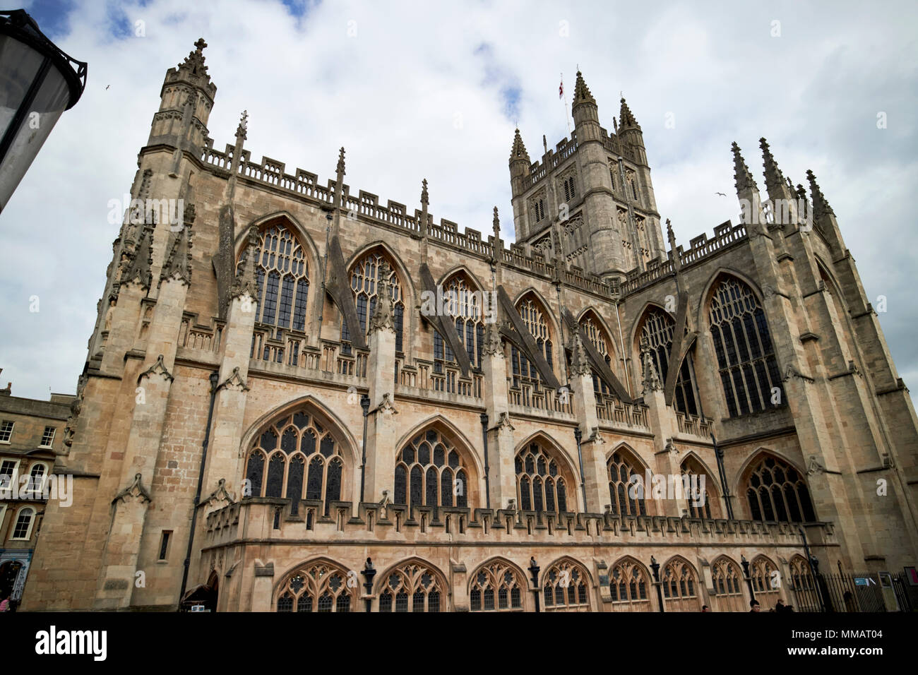 side view looking up at flying buttresses, battlements, pinnacles and parapets beneath the tower of gothic bath abbey Bath England UK Stock Photo