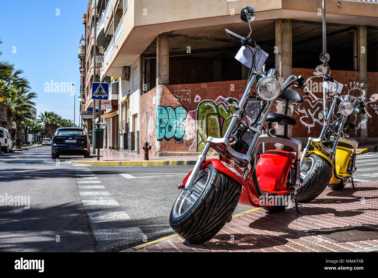 Electric Scooter hire. Rent it CB scooter rental motorbike. Bright coloured  electric bikes on street in Guardamar, Spain. Spanish Med town Stock Photo  - Alamy