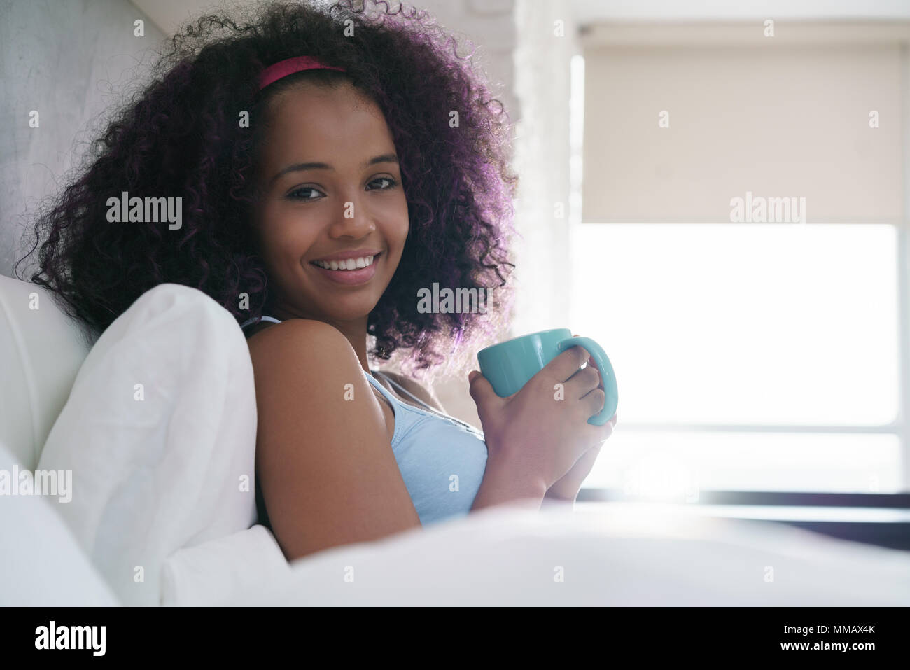 Girl Drinking Coffee In Bed Smiling At Camera Stock Photo