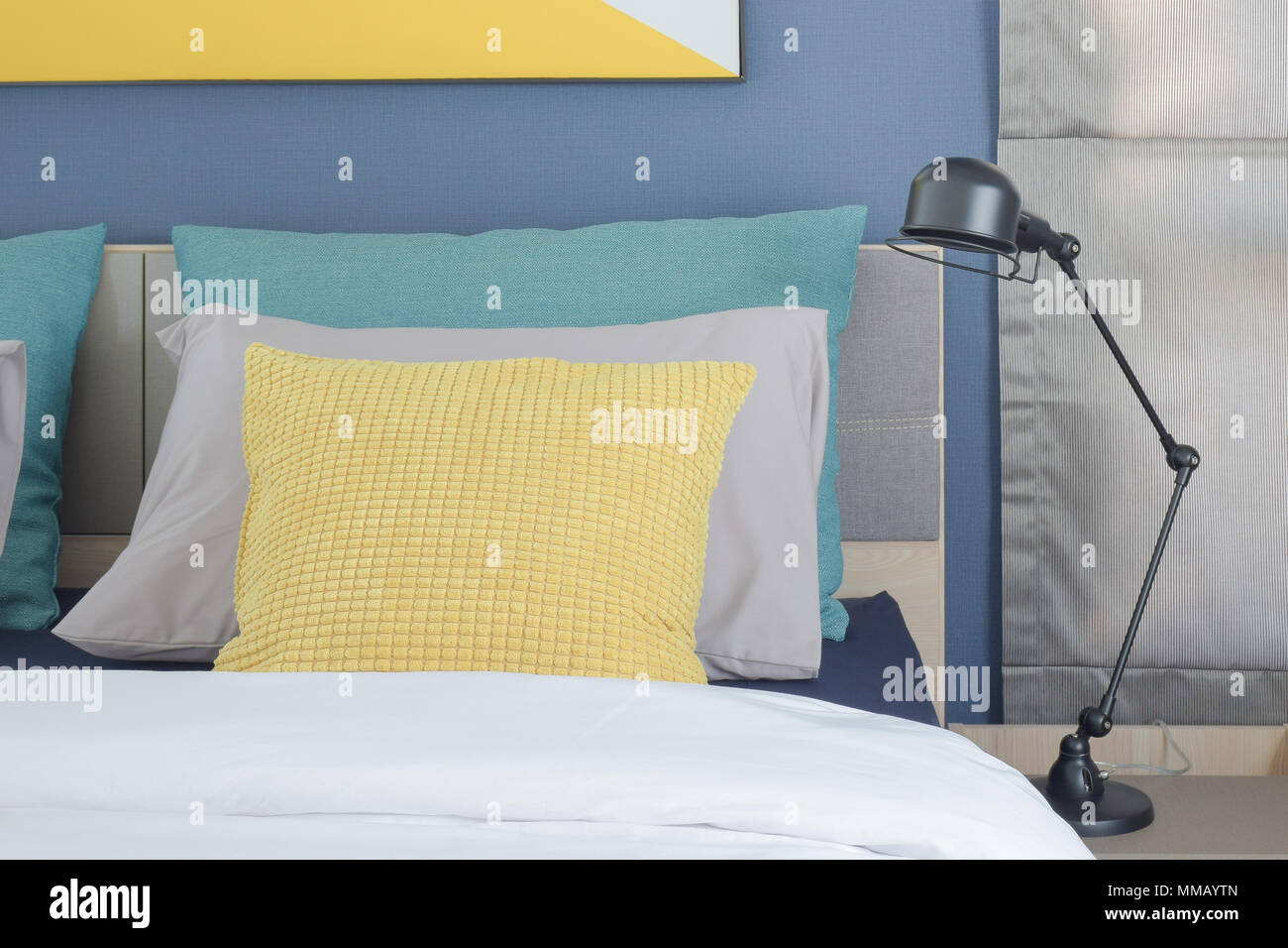 Yellow And Green Pillow On Bed With Black Foldable Lamp On Bedside