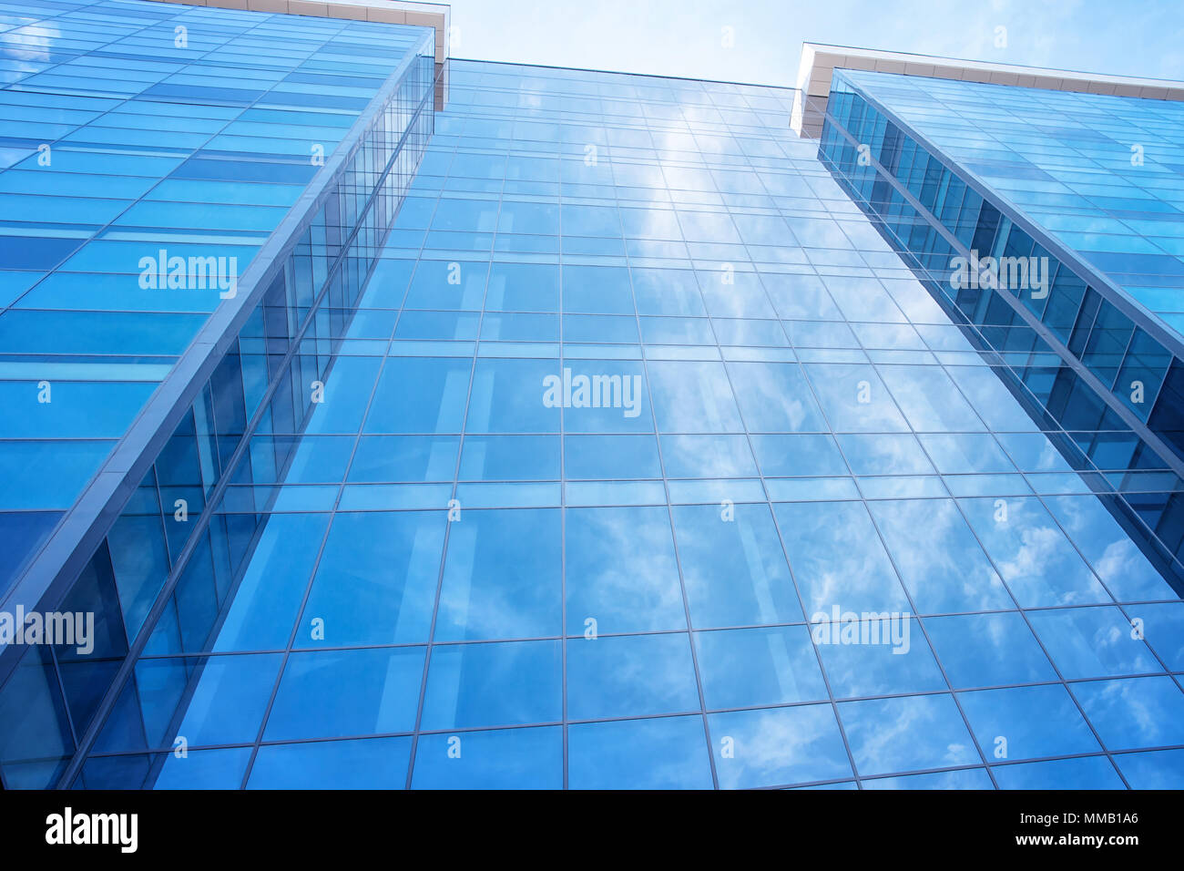 Blue glass modern office building wall with sky reflection. Stock Photo