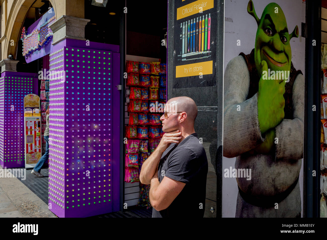 The fantasy monster Shrek and a bald man adopting the same postural echo outside a tourist trinket shop near Piccadilly Circus, on 9th May 2018, in London, England. Shrek is a 2001 American computer animated adventure fantasy comedy film loosely based on William Steig's 1990 fairy tale picture book Stock Photo