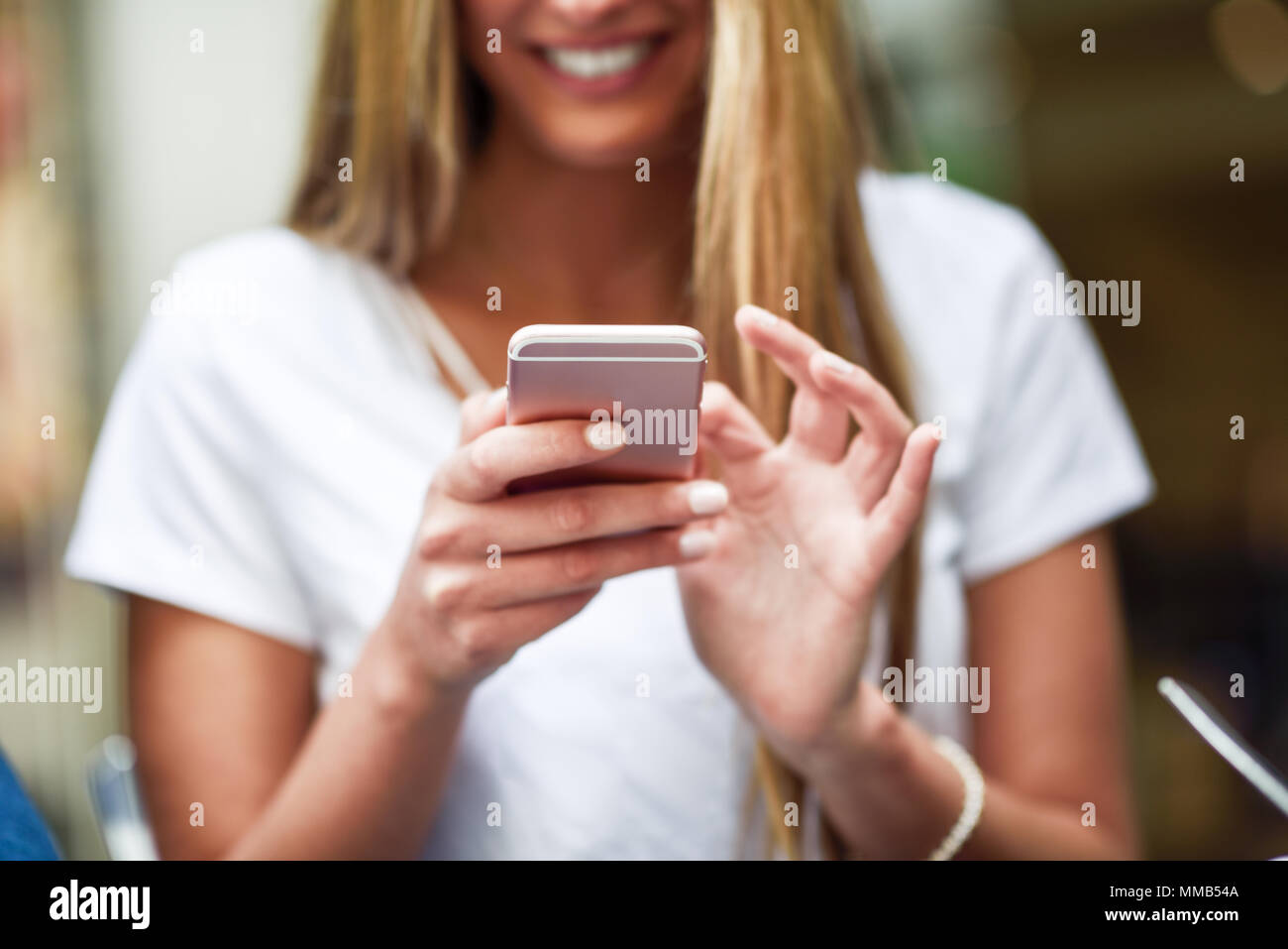 Close-up image of young blonde girl texting with smartphone, female hands typing text message via cellphone, social networking concept Stock Photo