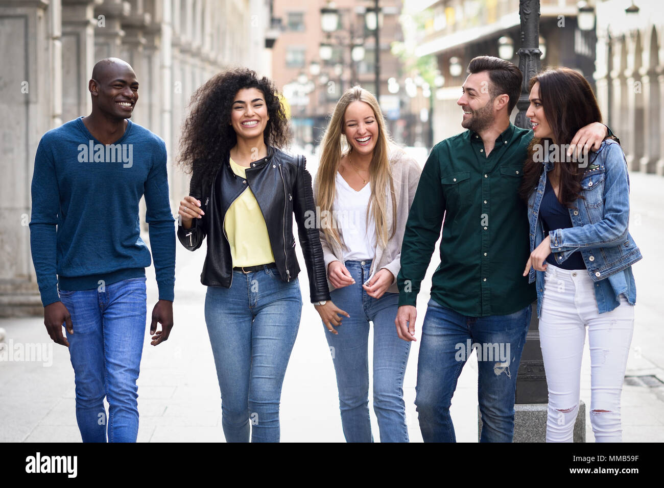 Multi-ethnic group of young people having fun together outdoors in urban background. group of people walking together Stock Photo