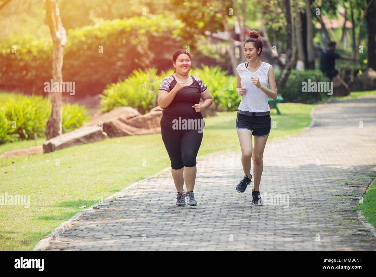 Two Asian girls fat and thin friend running jogging in the Park Stock Photo