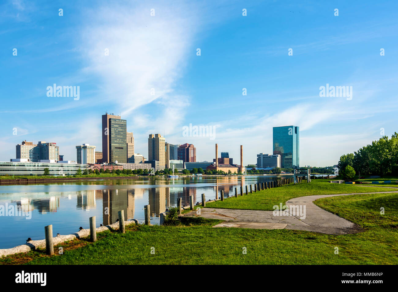 A panoramic view of downtown Toledo Ohio's skyline from across the Maumee River at a public park.  A beautiful blue sky reflecting in the river. Stock Photo