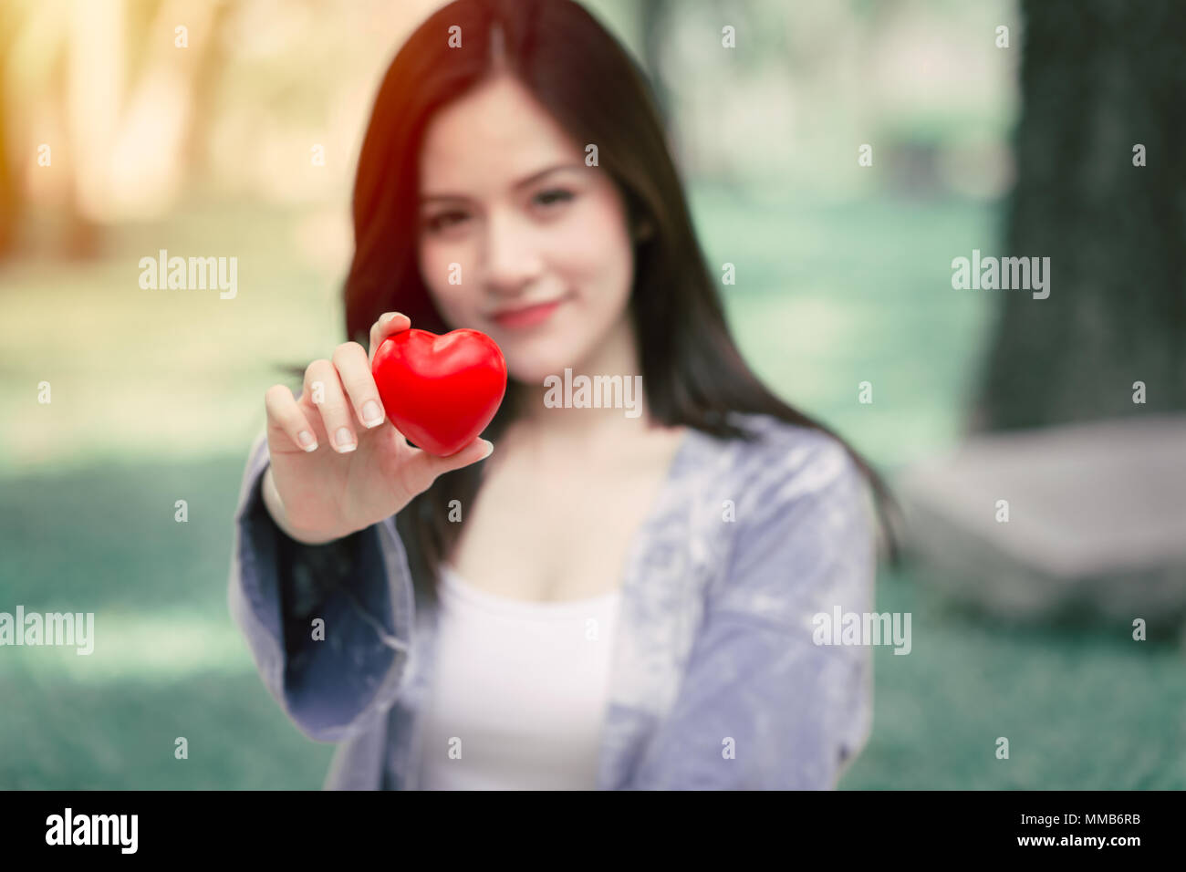 Giving Love together concept: Cute Asian woman hold red heart for loving sharing lovely vintage color tone Stock Photo