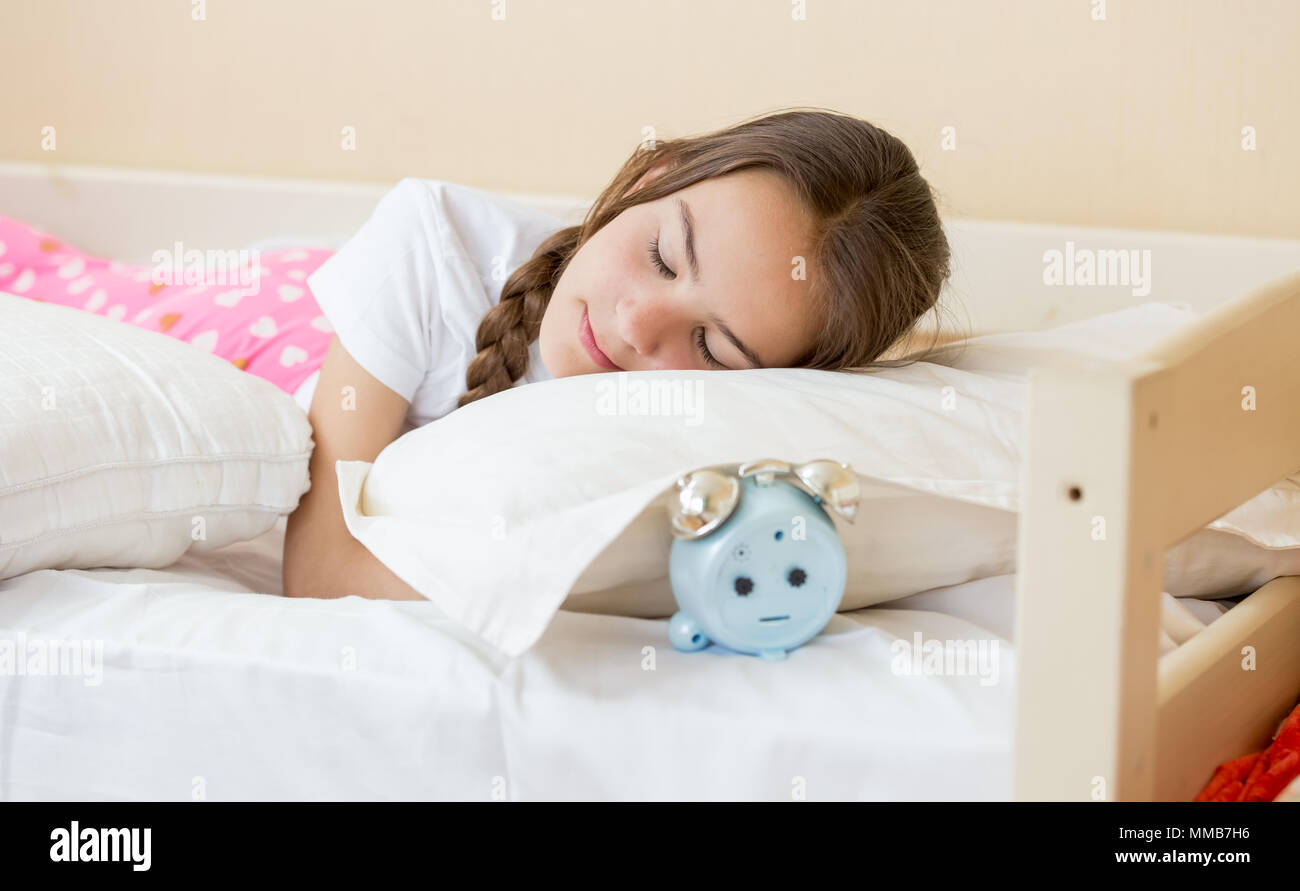 Closeup portrait of alarm clock lying under pillow in teenage girl
