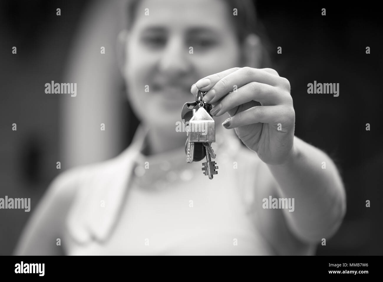 Closeup black and white portrait of smiling young woman holding keys ...