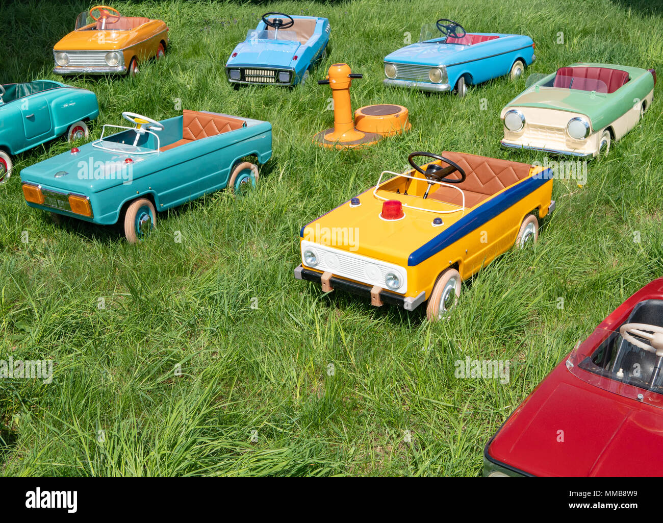 many childrens vintage toy pedal cars on green grass at playground