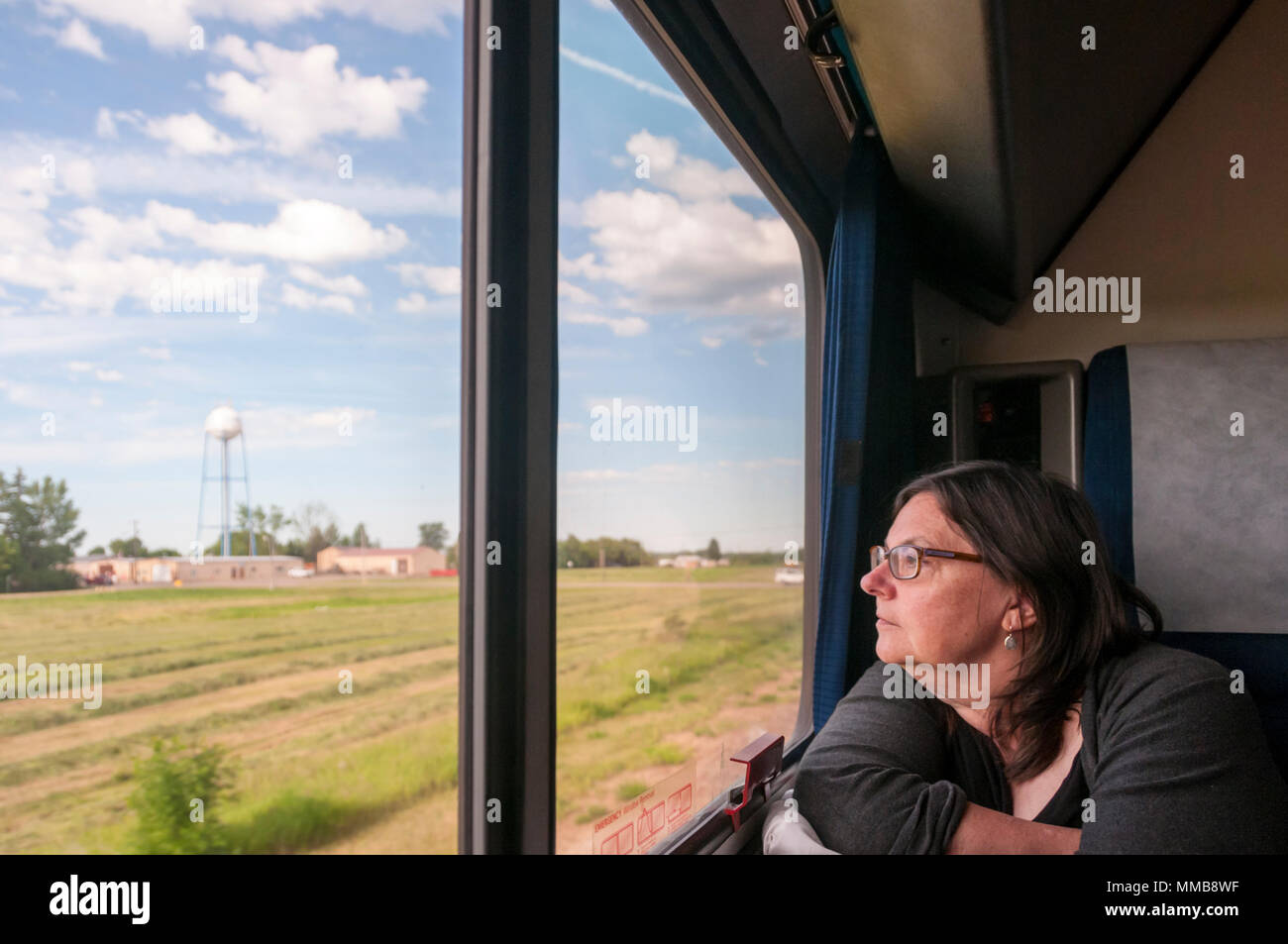 Woman looking out of window of Amtrak Empire Builder train crossing the American mid-west from Chicago to Seattle. Stock Photo