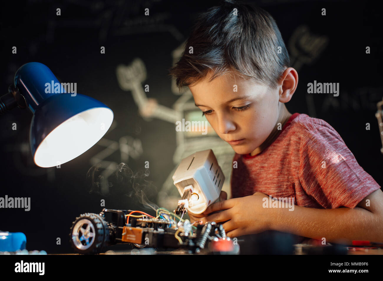 Boy enjoying his soldering hobby. Portrait of a skilled young boy working with a soldering gun. Stock Photo