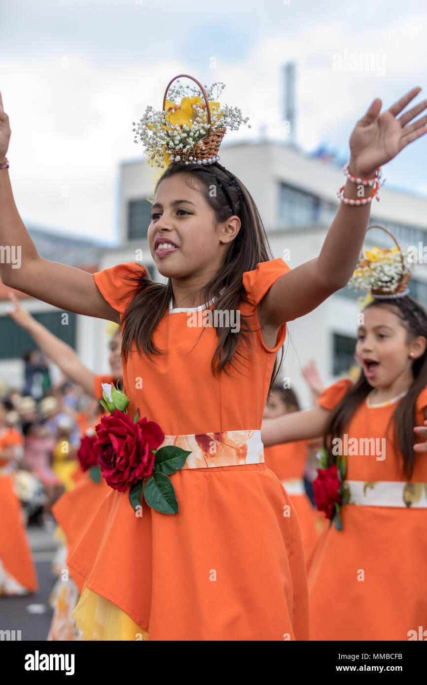 Funchal; Madeira; Portugal - April 22; 2018: A group of girls in orange costumes are dancing at Madeira Flower Festival Parade in Funchal on the Islan Stock Photo